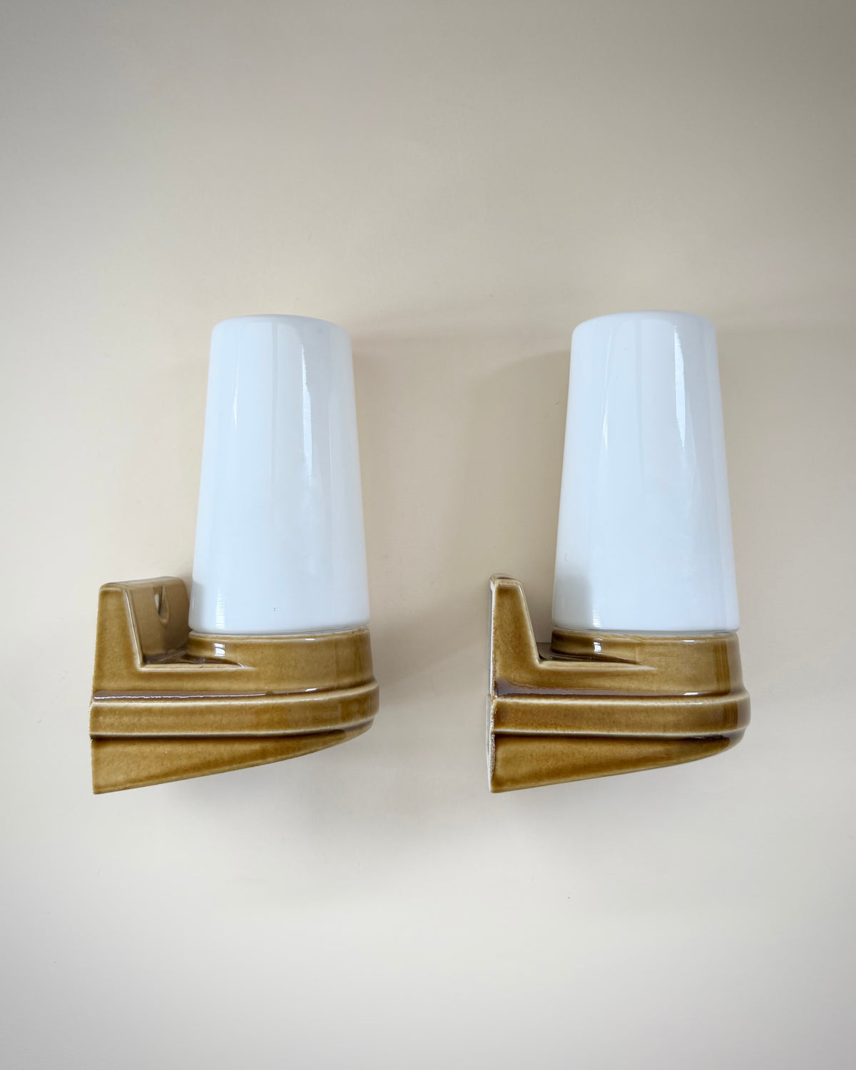 Front view of the caramel-brown glazed ceramic bases and white opal glass shades on the Ifö Bernadotte wall lamps.
