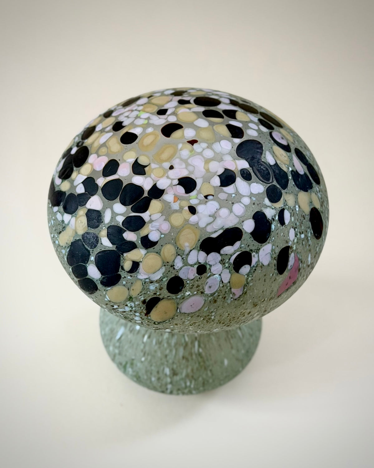 Underside view of the green glass mushroom showing the base and moulded glass surface.