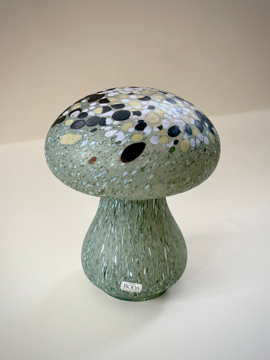 Side view of the green glass mushroom showing its rounded cap and organically shaped stem.