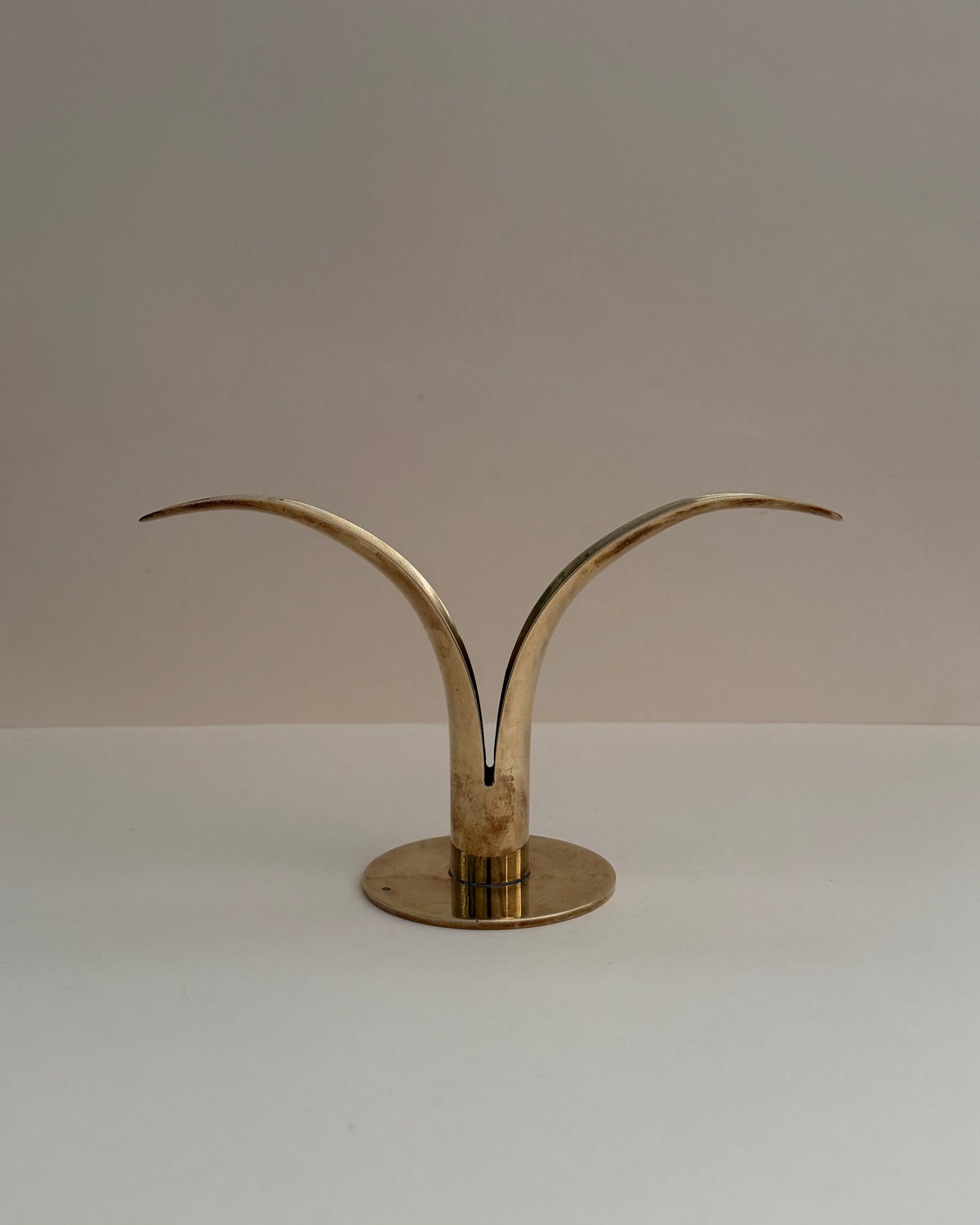 Ystad Metall Liljan solid brass candlestick, front view with two curved lily-like wings and circular base.