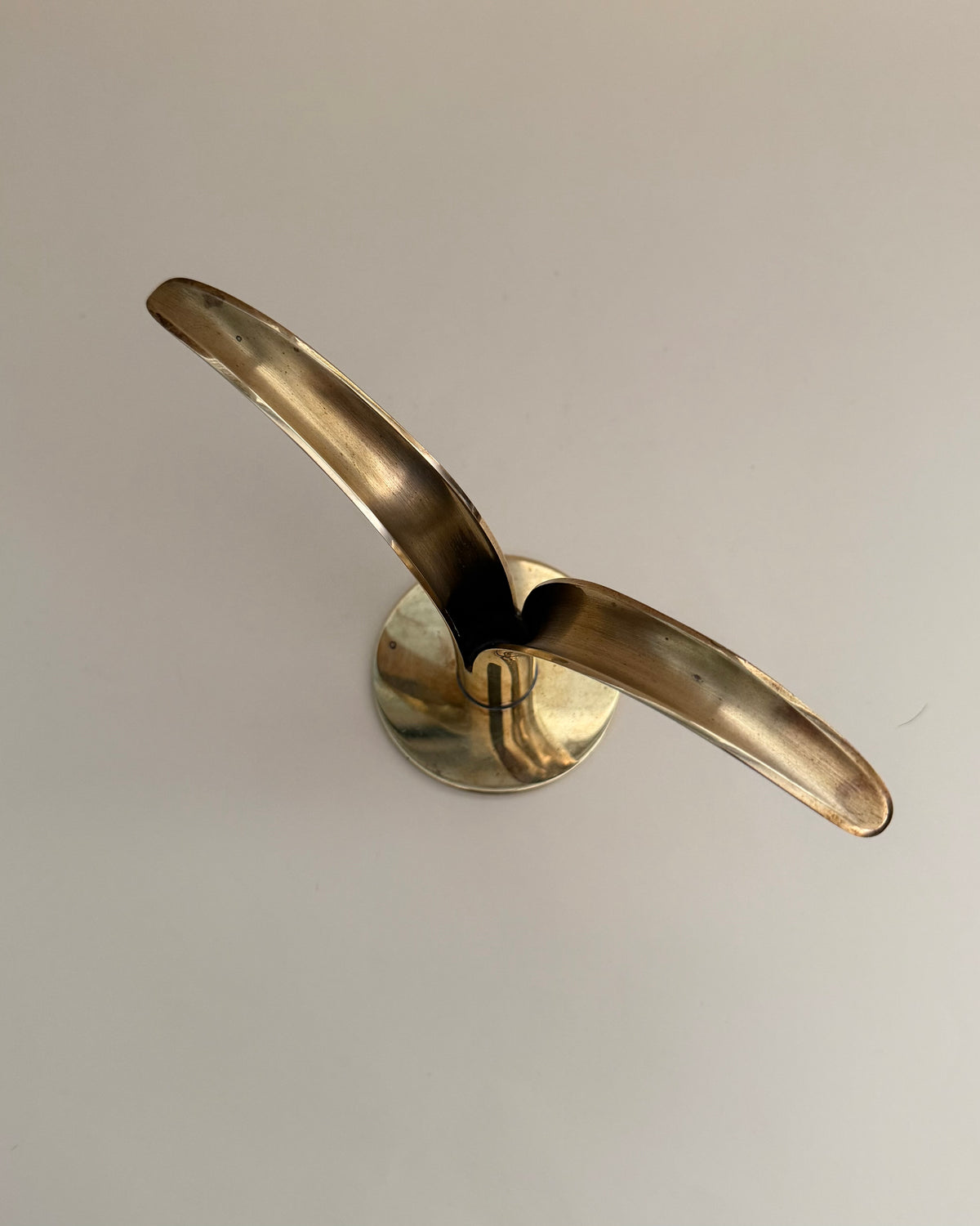 Side view showing the sculptural curved brass wings and round base of the Ystad Metall Liljan candlestick.